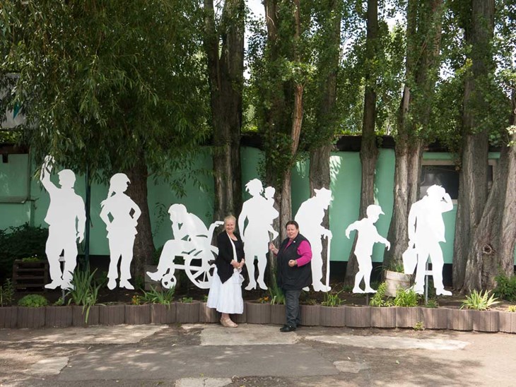 Ehemalige Bezirksbürgermeisterin und Geschäftsführerin vor der sozialen Skulptur "weiße Botschaft" von Joy Lohmann, die Langzeitarbeitslose darstellen soll.