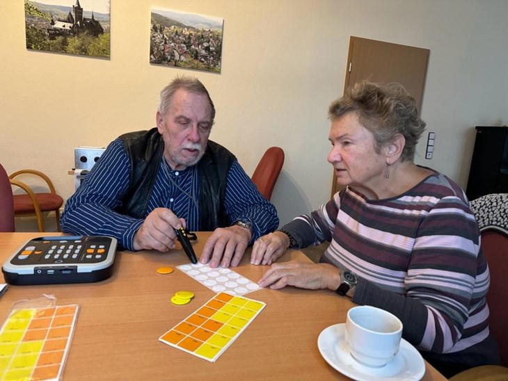 Dagmar K. erklärt Rolf Z. ein Hilfsmittel, den Penfriend 